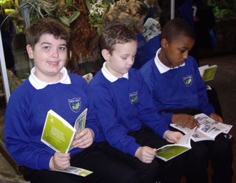 Jamie, Bailey and Dray from New Oak Primary reading by the orchid display in Bristol Zoo Gardens' reptile house.